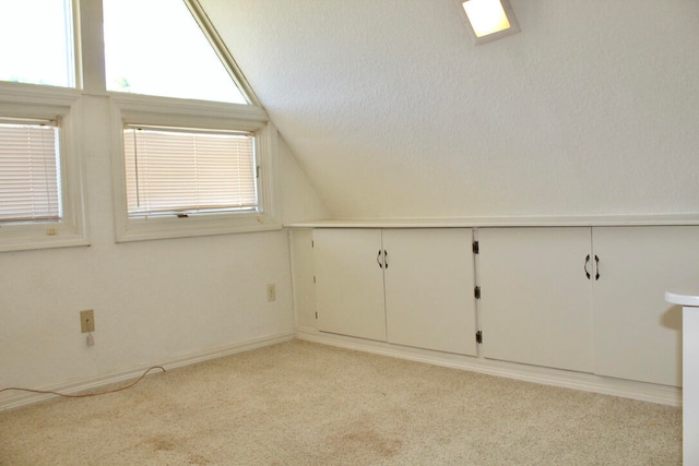 bonus room with a textured ceiling, light colored carpet, and lofted ceiling