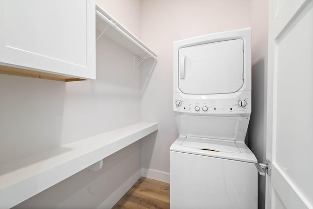 laundry area featuring cabinets, light wood-type flooring, and stacked washer and dryer