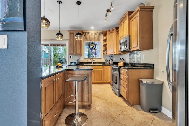 kitchen featuring sink, decorative light fixtures, a kitchen bar, light tile patterned floors, and appliances with stainless steel finishes