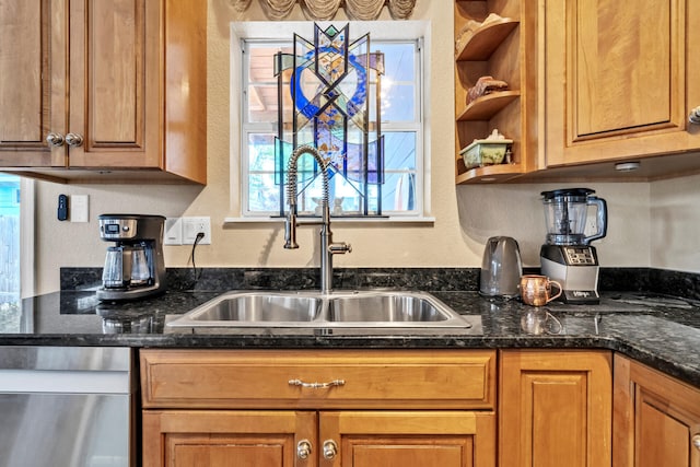 kitchen with dark stone countertops, sink, and stainless steel dishwasher