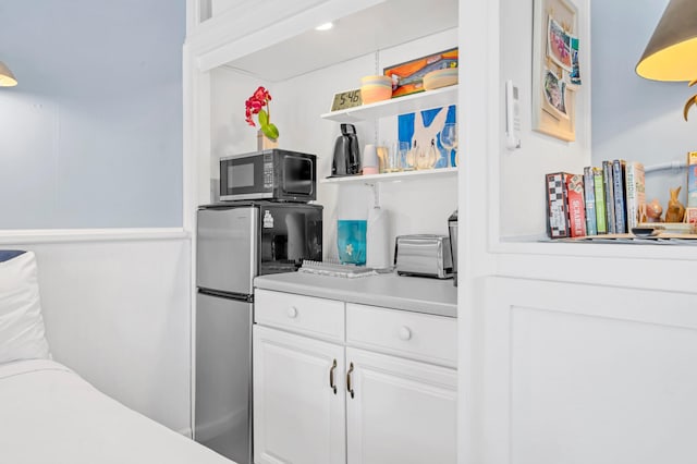 kitchen with stainless steel refrigerator and white cabinetry