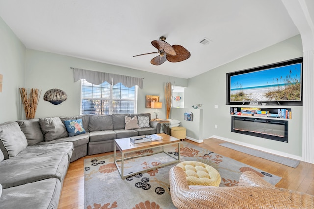 living room featuring ceiling fan, light hardwood / wood-style flooring, and vaulted ceiling