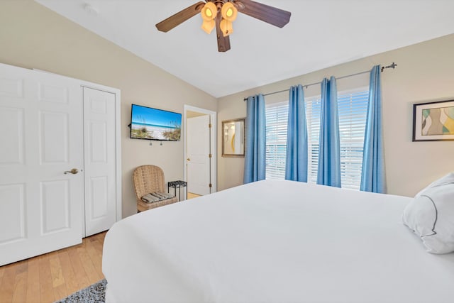 bedroom with a closet, hardwood / wood-style flooring, ceiling fan, and lofted ceiling