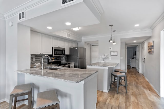 kitchen featuring a kitchen bar, kitchen peninsula, hanging light fixtures, and stainless steel appliances