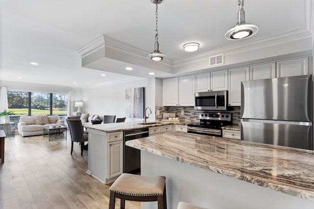 kitchen featuring kitchen peninsula, light stone countertops, pendant lighting, and stainless steel appliances