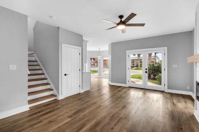 unfurnished living room with a large fireplace, dark hardwood / wood-style flooring, ceiling fan, and french doors