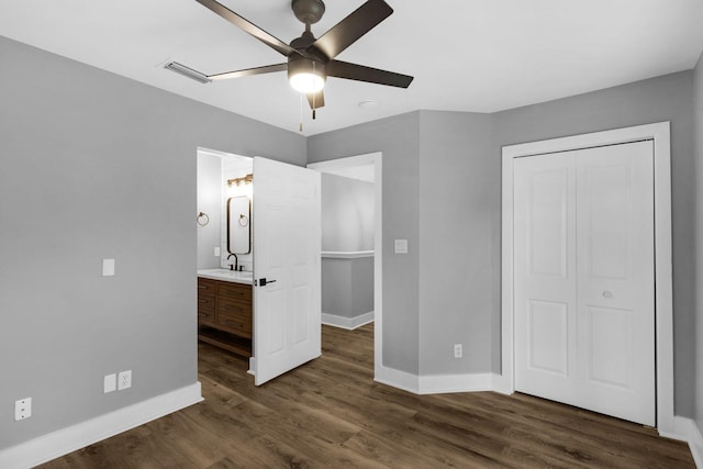 unfurnished bedroom with ceiling fan, dark hardwood / wood-style floors, a closet, and ensuite bath