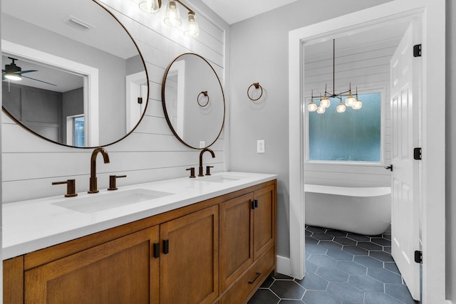 bathroom featuring tile patterned flooring, ceiling fan, vanity, and a washtub