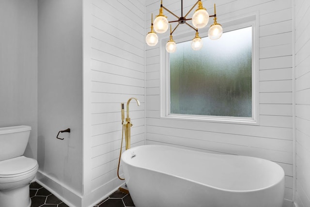 bathroom with tile patterned flooring, toilet, a tub to relax in, and a wealth of natural light