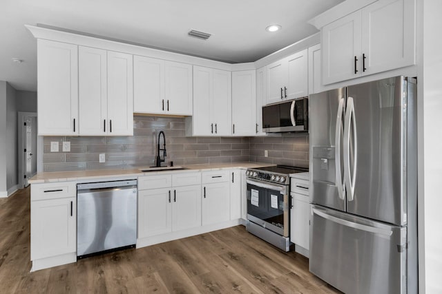 kitchen with sink, stainless steel appliances, dark hardwood / wood-style flooring, backsplash, and white cabinets