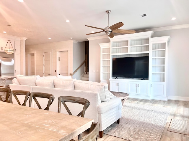 living room with light hardwood / wood-style floors, ceiling fan, and crown molding