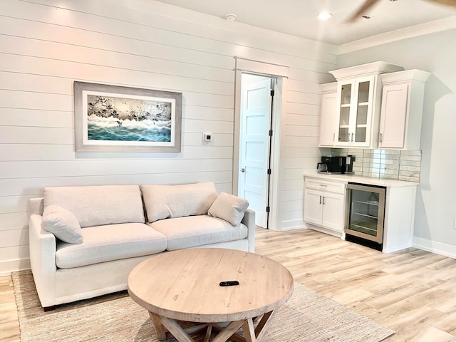 living room with bar area, light hardwood / wood-style floors, beverage cooler, and wooden walls