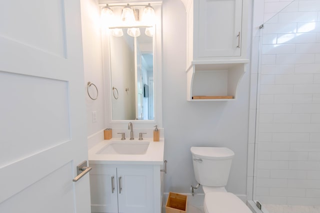 bathroom featuring vanity, toilet, and tiled shower