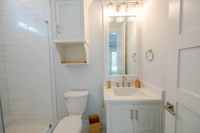 bathroom with tiled shower, vanity, and toilet