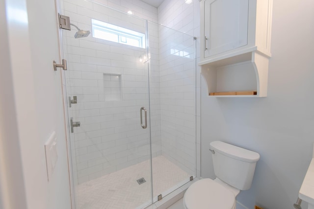 bathroom featuring a shower with door and toilet