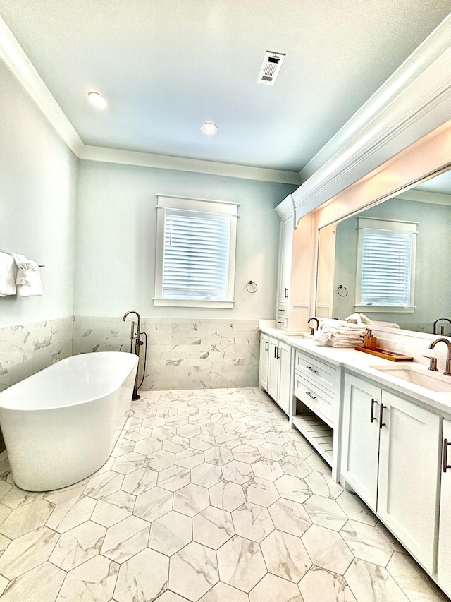 bathroom featuring vanity, tile walls, a wealth of natural light, and a tub