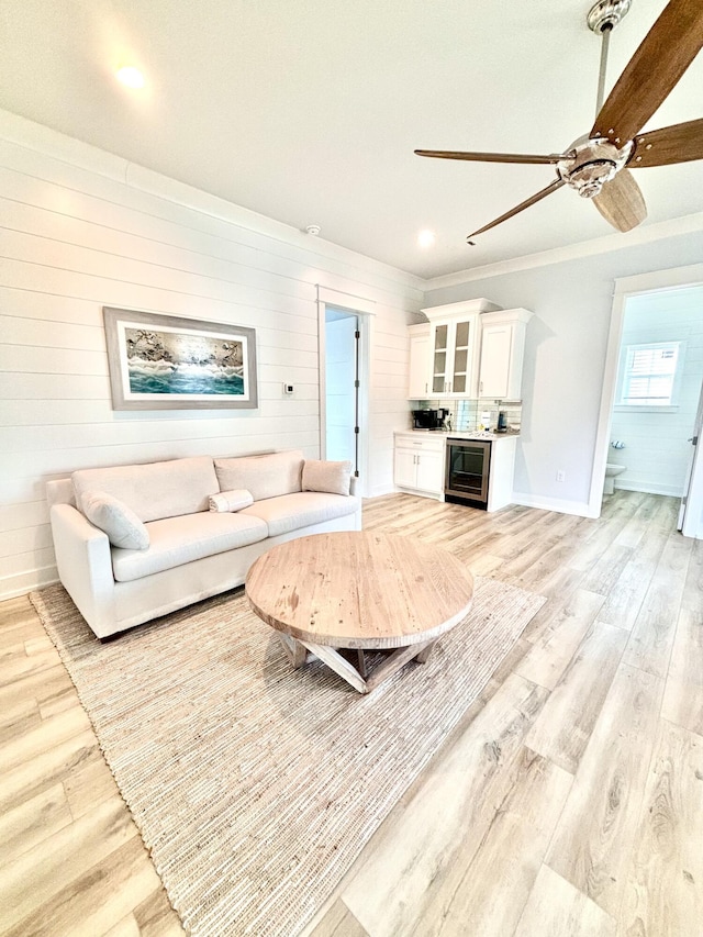 living room with wine cooler, crown molding, and light hardwood / wood-style floors