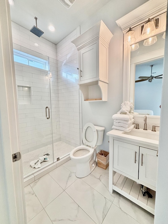 bathroom featuring ceiling fan, a shower with door, vanity, and toilet