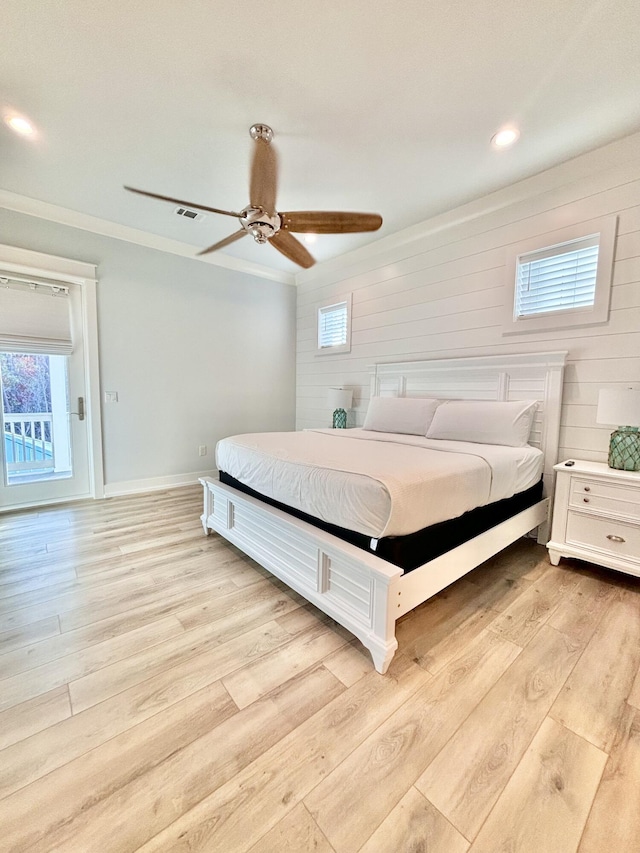 bedroom featuring ceiling fan, wood walls, access to exterior, and light wood-type flooring