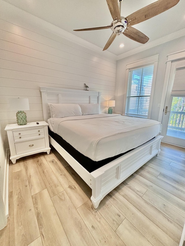 bedroom with wood walls, ceiling fan, light hardwood / wood-style floors, and access to exterior