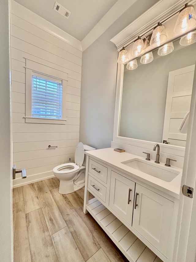 bathroom featuring wood-type flooring, vanity, toilet, and wood walls