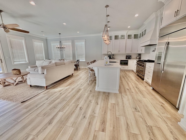 kitchen featuring light wood-type flooring, stainless steel appliances, a kitchen island with sink, crown molding, and white cabinetry