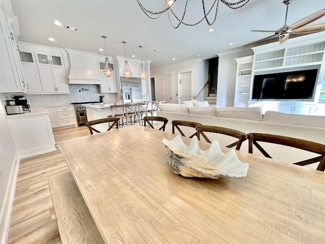 dining space with crown molding, light hardwood / wood-style floors, and ceiling fan with notable chandelier