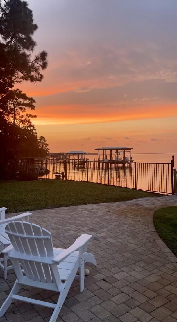 patio terrace at dusk with a lawn and a water view