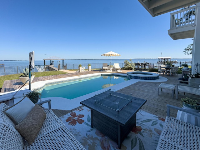 view of pool featuring a deck with water view and an in ground hot tub