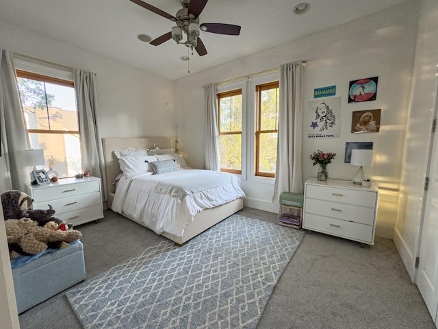 bedroom featuring multiple windows, light colored carpet, and ceiling fan