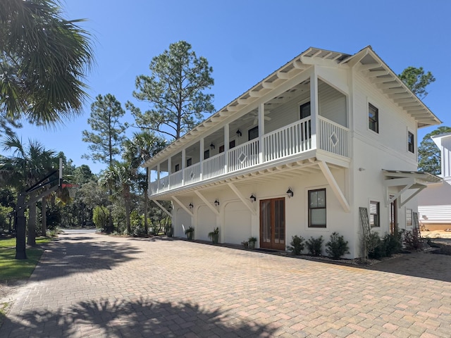 view of front of house with a garage, a balcony, and french doors