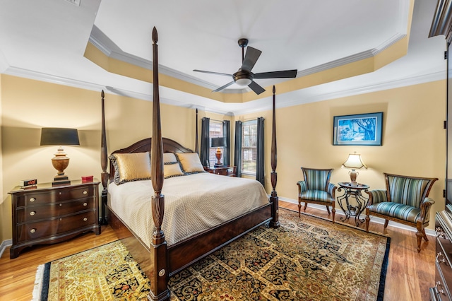 bedroom featuring a tray ceiling, ceiling fan, ornamental molding, and hardwood / wood-style flooring