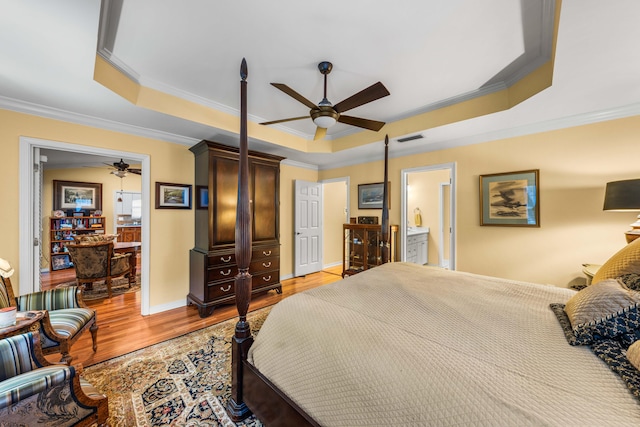 bedroom featuring a raised ceiling, ceiling fan, and light wood-type flooring