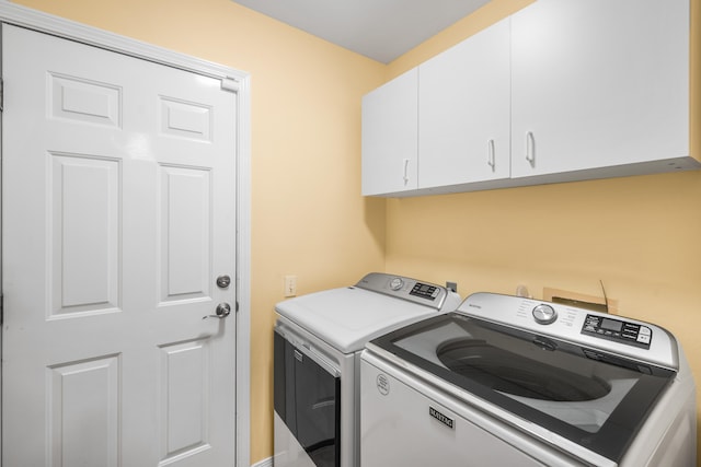 washroom with washing machine and clothes dryer and cabinets