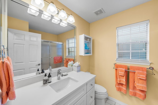 bathroom featuring tile patterned floors, vanity, toilet, and a shower with shower door