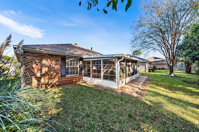 rear view of house featuring a sunroom and a lawn