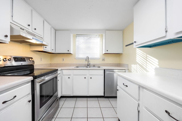 kitchen featuring appliances with stainless steel finishes, light tile patterned floors, white cabinetry, and sink