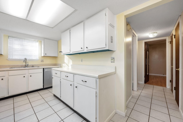 kitchen featuring white cabinets, dishwasher, light tile patterned floors, and sink