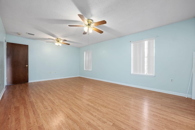 empty room with a wealth of natural light, light hardwood / wood-style flooring, ceiling fan, and a textured ceiling