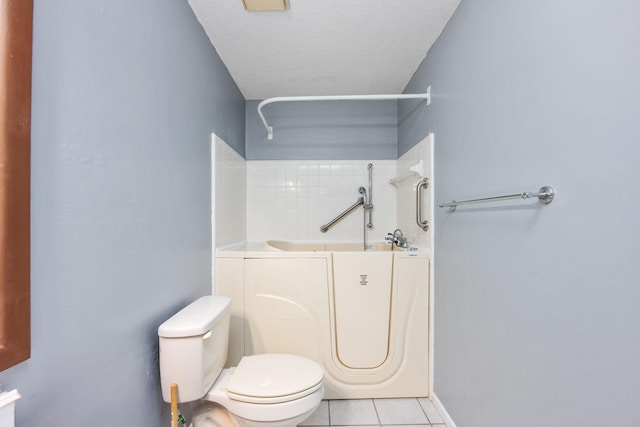 bathroom with a washtub, tile patterned flooring, a textured ceiling, and toilet