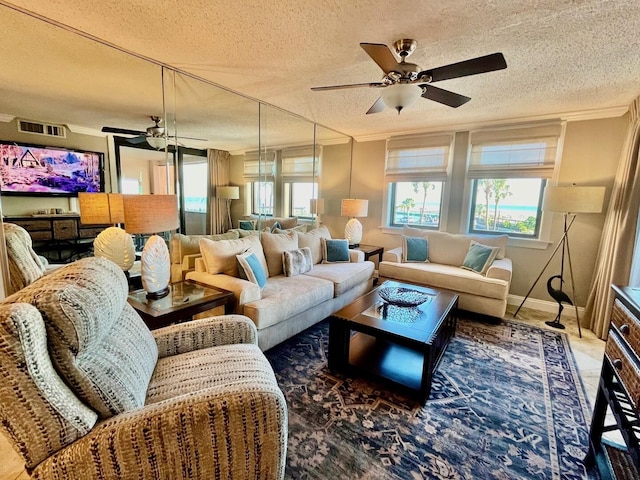 living room with crown molding, ceiling fan, and a textured ceiling