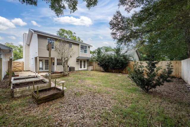 back of house with cooling unit, a yard, and french doors