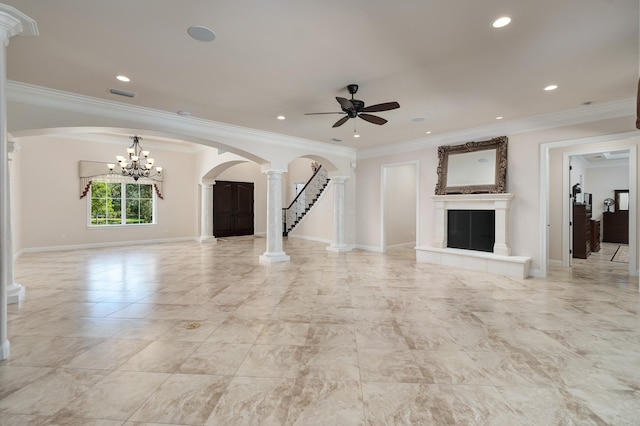 unfurnished living room featuring ceiling fan with notable chandelier, ornate columns, ornamental molding, and a tiled fireplace