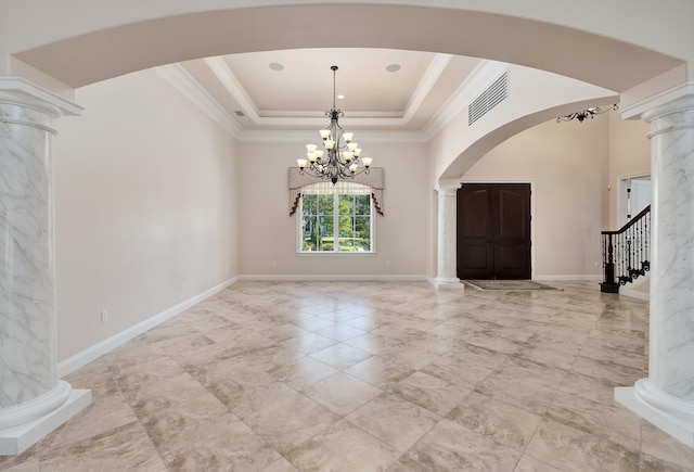 foyer entrance with a notable chandelier, a raised ceiling, crown molding, and decorative columns