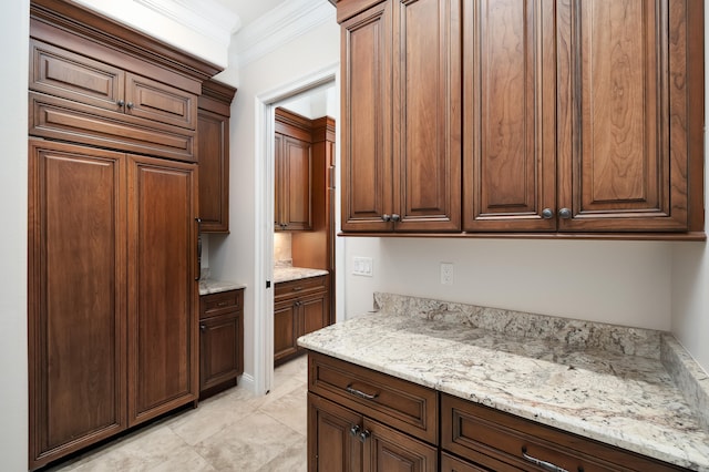 kitchen with light stone counters, ornamental molding, and light tile patterned flooring