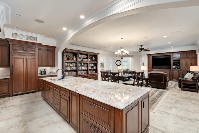 kitchen featuring pendant lighting, sink, ornamental molding, an island with sink, and paneled fridge