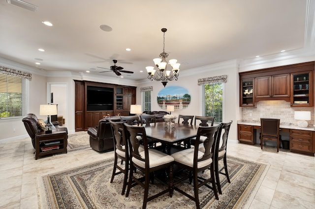 dining area with a wealth of natural light, built in desk, ceiling fan with notable chandelier, and ornamental molding