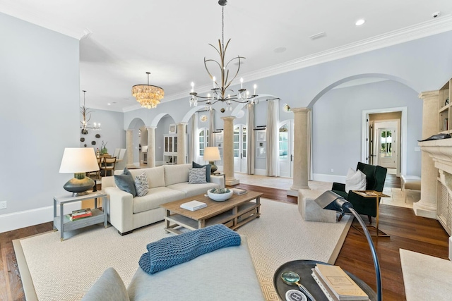 living room with a high end fireplace, ornate columns, ornamental molding, wood-type flooring, and a notable chandelier