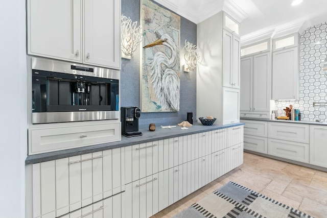 kitchen featuring tasteful backsplash, white cabinetry, stainless steel oven, and crown molding