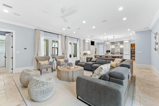 living room with ceiling fan with notable chandelier and crown molding